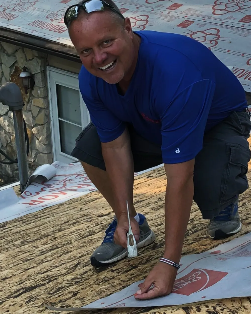 Brad VanBibber, owner of All-American Restoration, Inc., laying underlayment on a roof